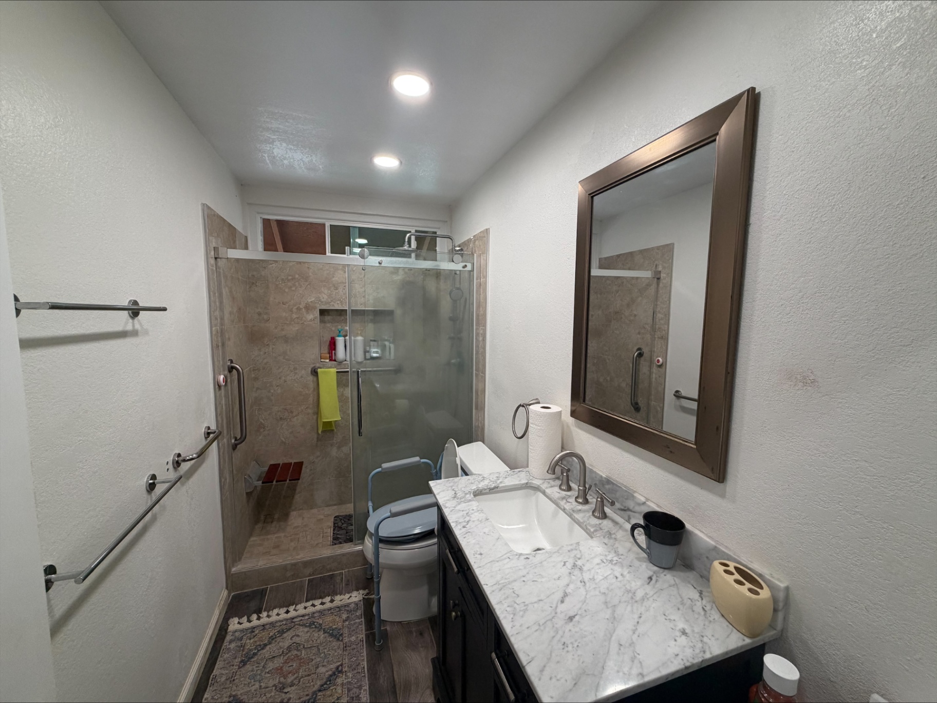 Accessible resident bathroom with walk-in shower, grab bars, and marble vanity