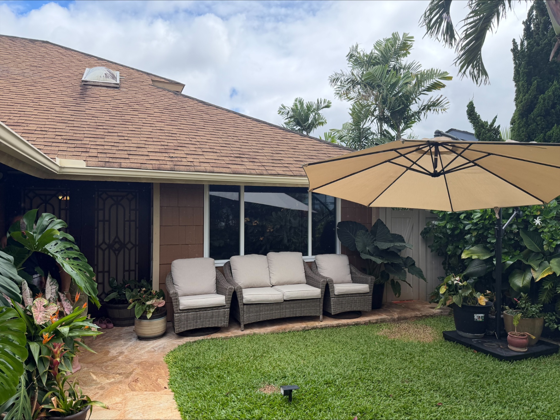 Front lanai seating area under a tropical umbrella